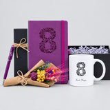 Coffret 8 mars déballé : carnet violet gravé au nom, mug blanc au 8 fleuri, stylo violet dans son étui et fleurs séchées