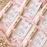 Éventails en bois ajouré noués d'un ruban organza rose sur des cartes de remerciement mariage à fleurs de cerisier
